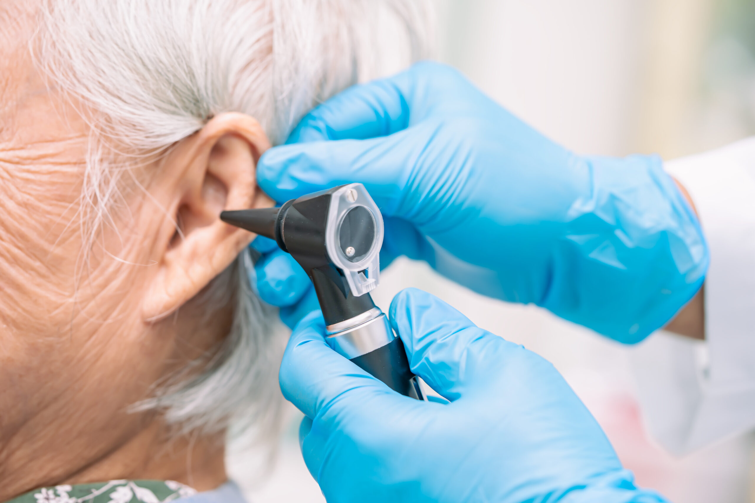 Audiologist or ENT doctor use otoscope checking ear of asian sen